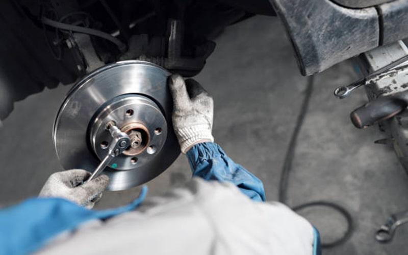 Technician inspecting a brake disc with the wheel removed