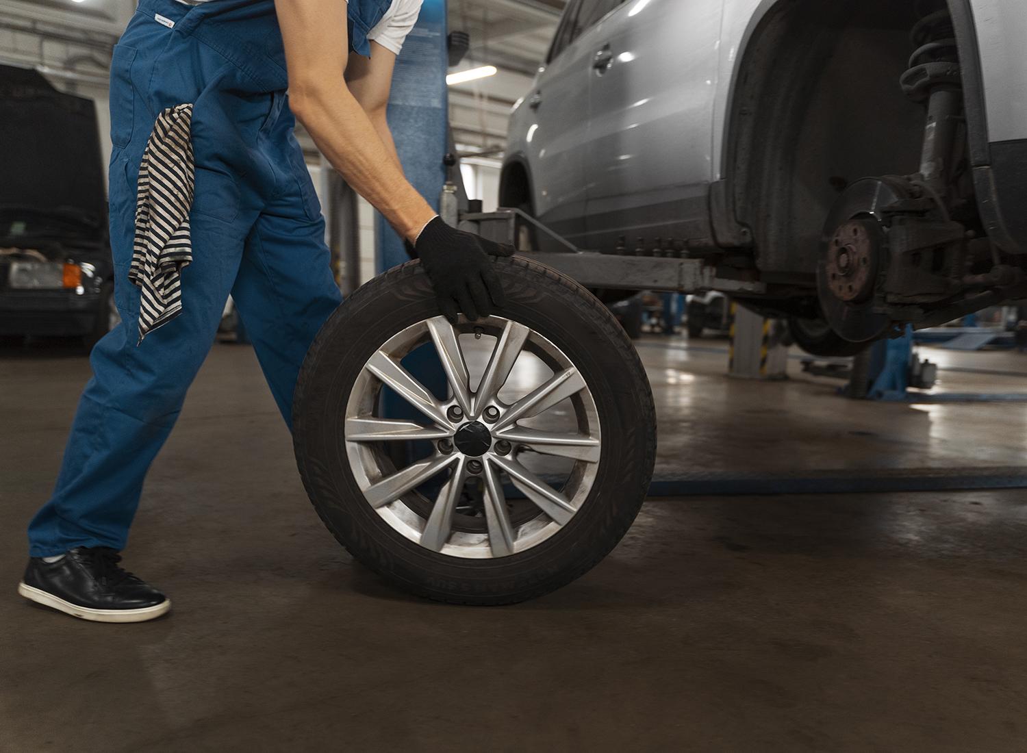 A wheel removed beside a raised car during workshop service