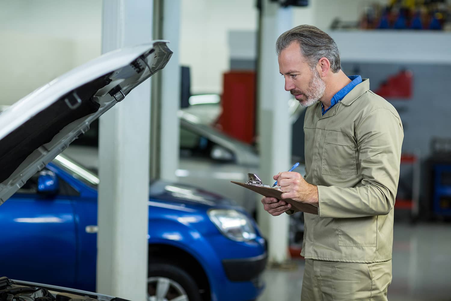Technician examining a car with the hood open