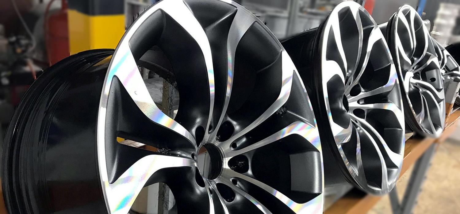 Black and silver alloy wheels arranged on a workshop bench