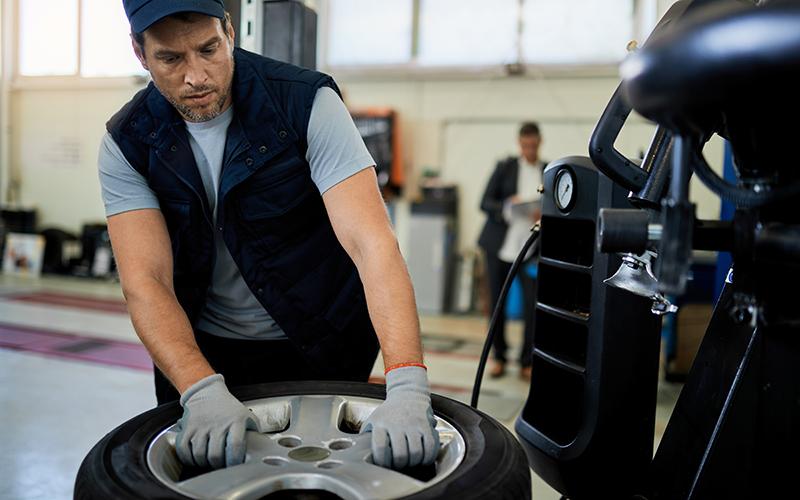 Technician handling a wheel at tire service equipment