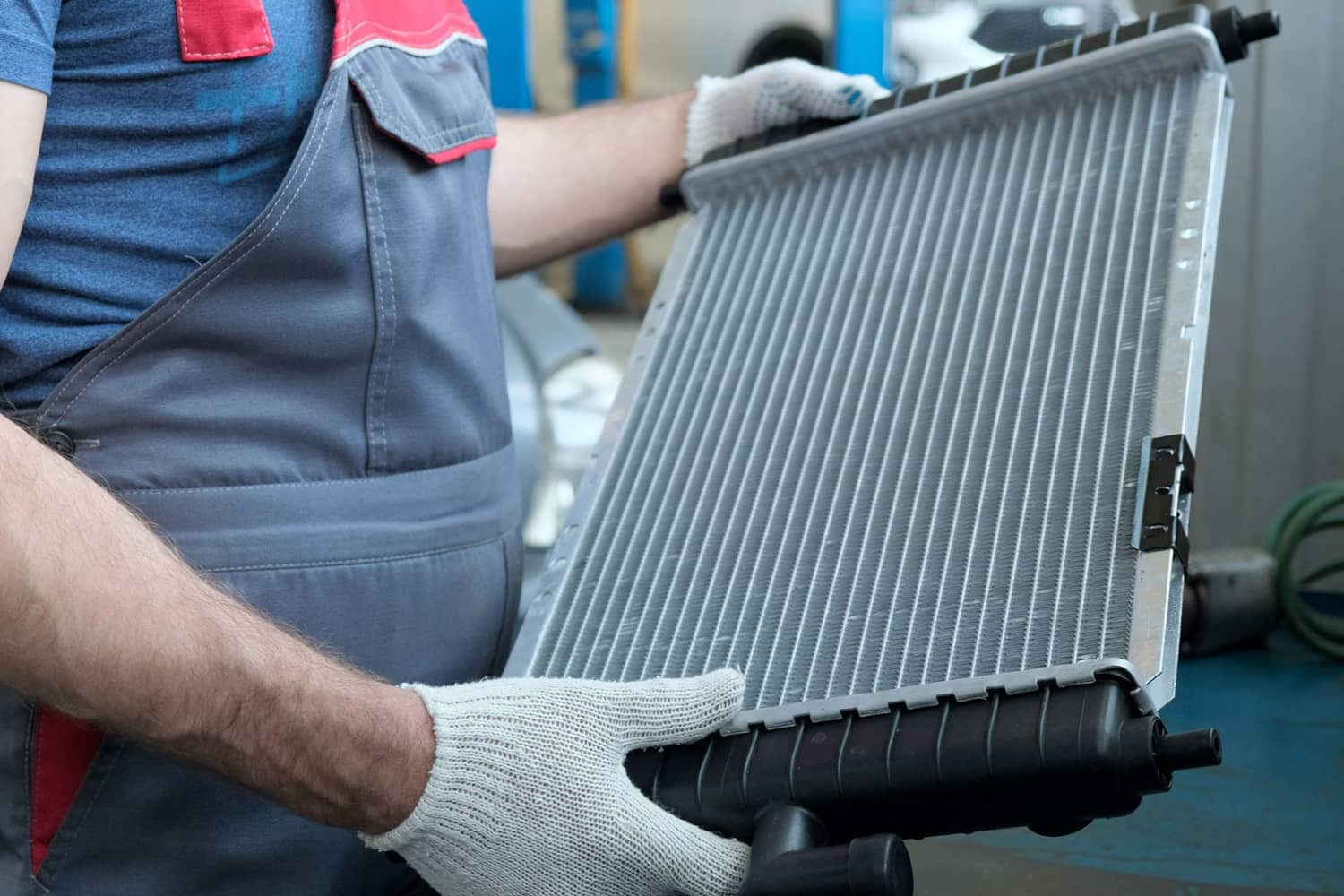 Technician holding a car radiator for inspection or replacement