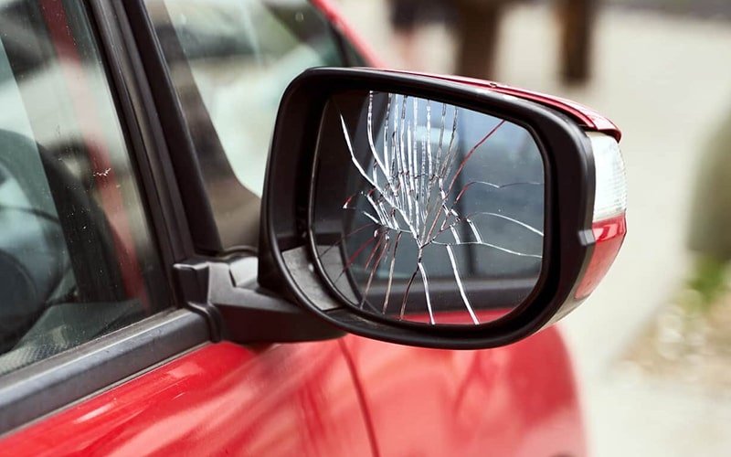 Cracked exterior mirror glass on a red car