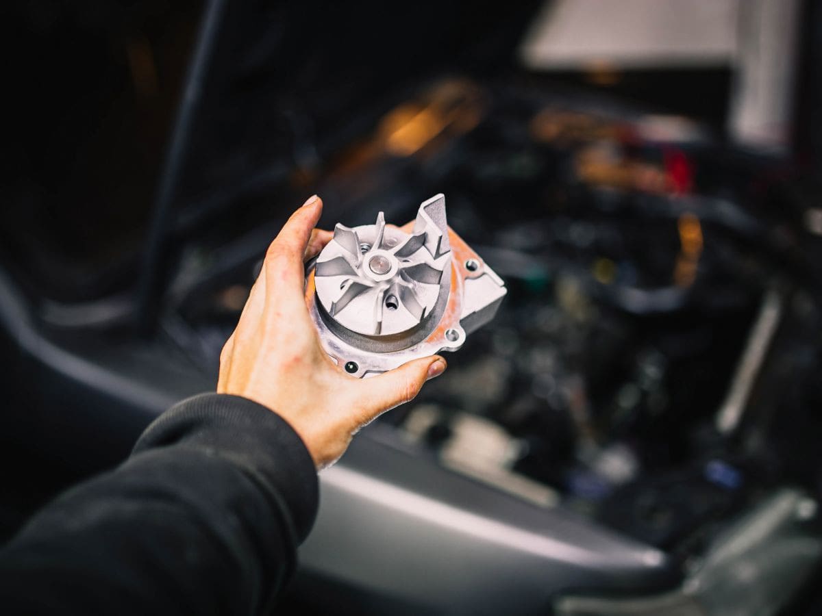 Water pump held beside an engine during a replacement inspection