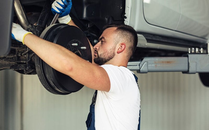 Technician working at the front suspension of a car on a lift