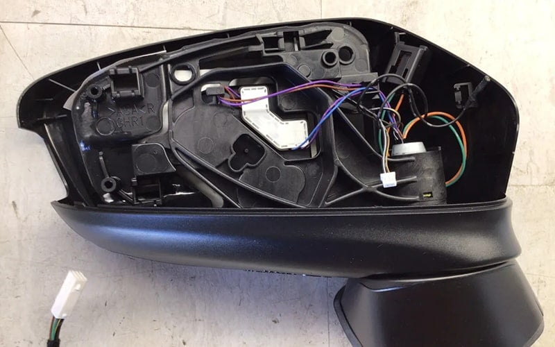 Opened side mirror housing showing its internal mechanism and wiring