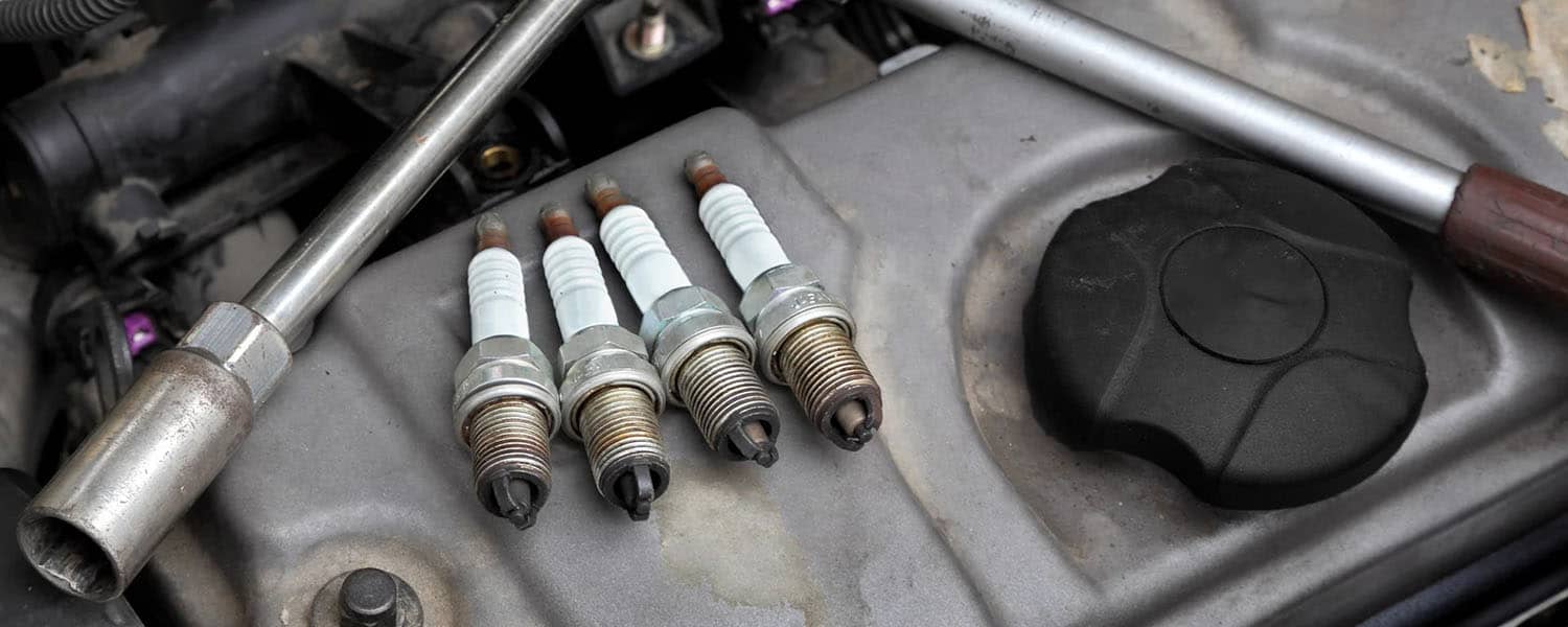 Removed spark plugs and a socket tool on an engine cover