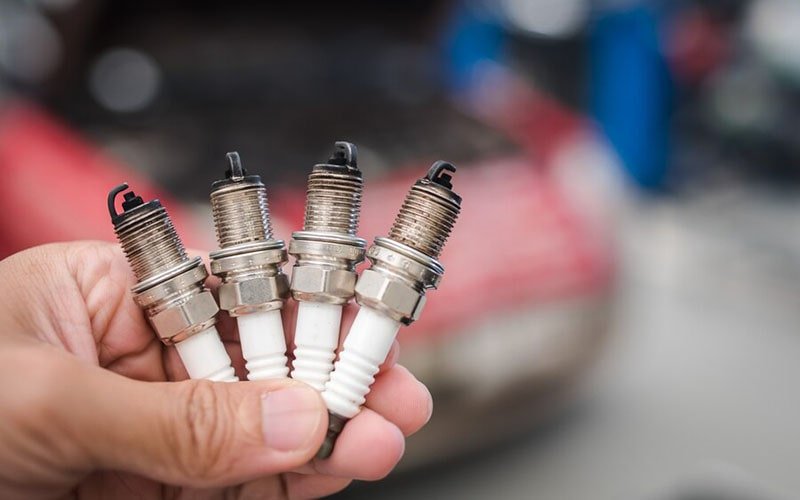 Four removed spark plugs held together for inspection