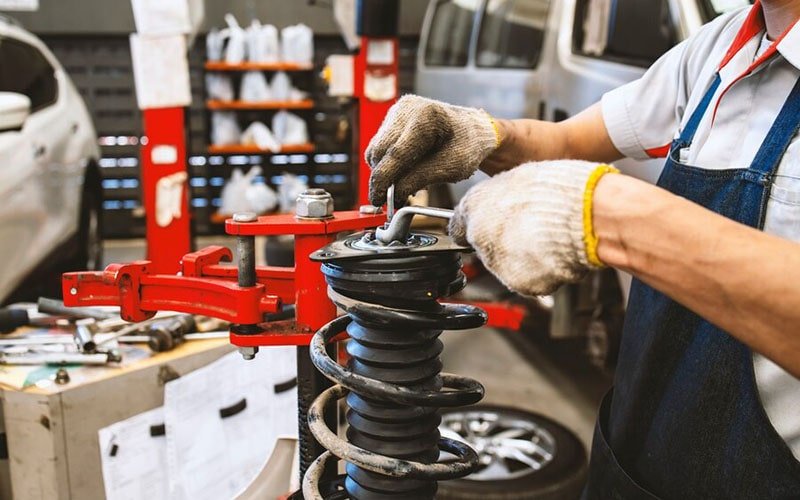 Technician handling a coil spring and strut in a spring compressor