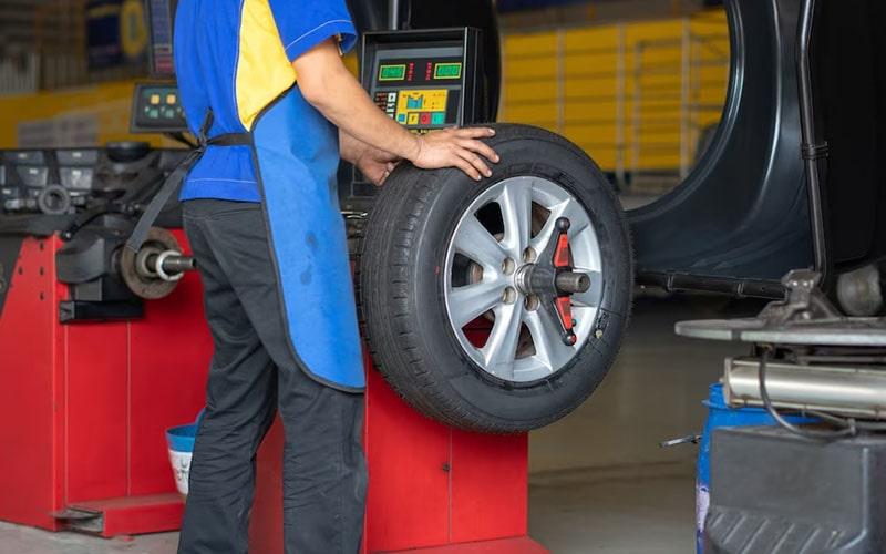 Technician using a wheel balancing machine with a removed wheel