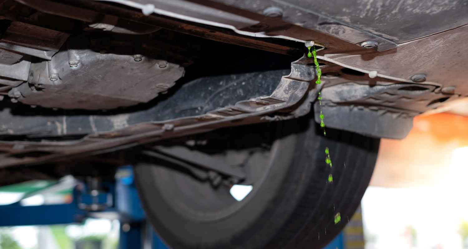 Green coolant draining beneath a raised vehicle