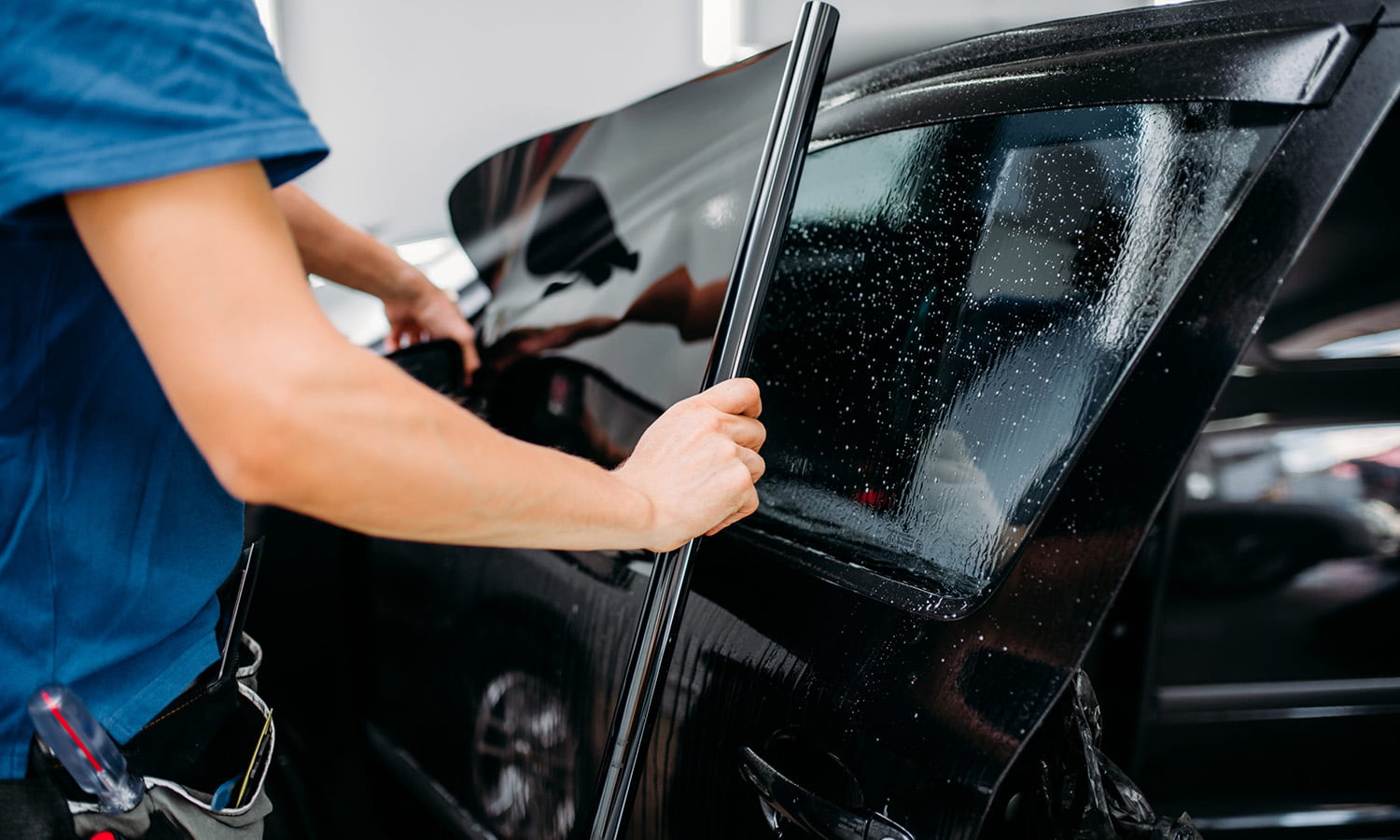 Installer smoothing window film onto a car door glass