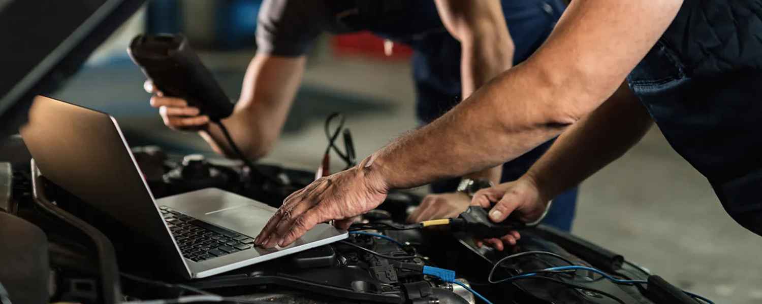 Technicians using electrical test equipment and a laptop at an engine bay