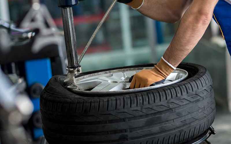 Technician fitting a tire to a wheel on workshop equipment