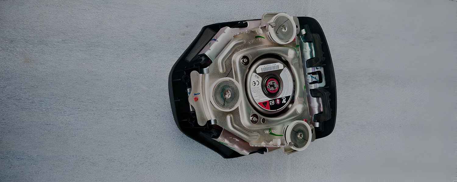 Rear housing and inflator of a removed steering-wheel airbag assembly