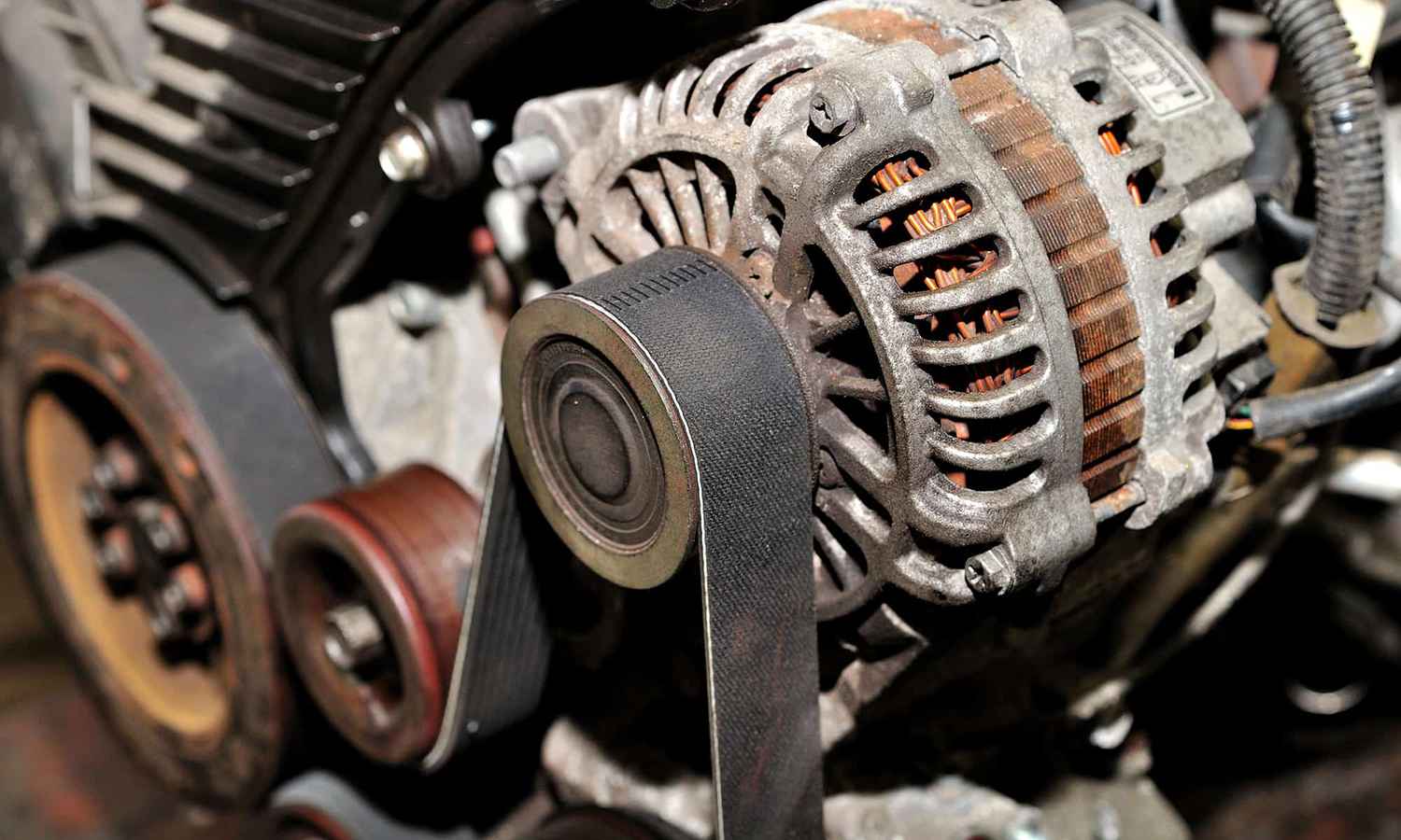 Belt-driven alternator and pulley installed beside the engine