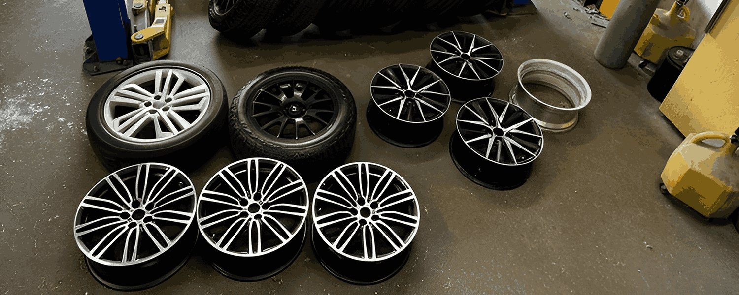 Different alloy wheel designs and finishes laid out in a workshop