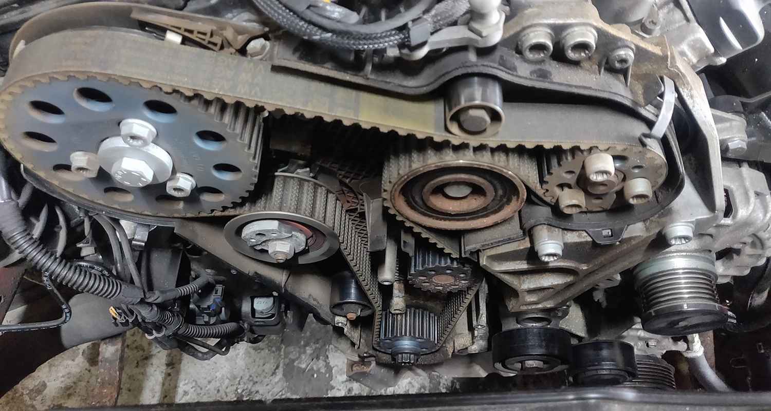 Exposed toothed timing belt and engine pulleys