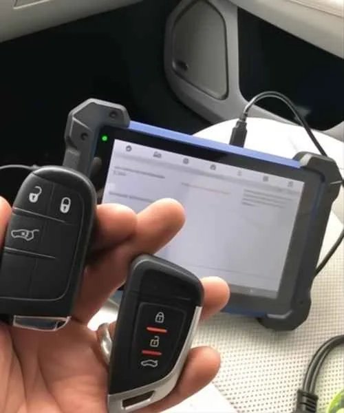 Two remote car keys beside a diagnostic tablet