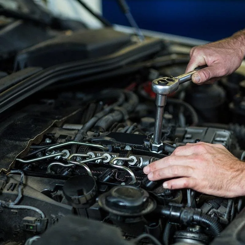 Hands using a socket tool on an engine