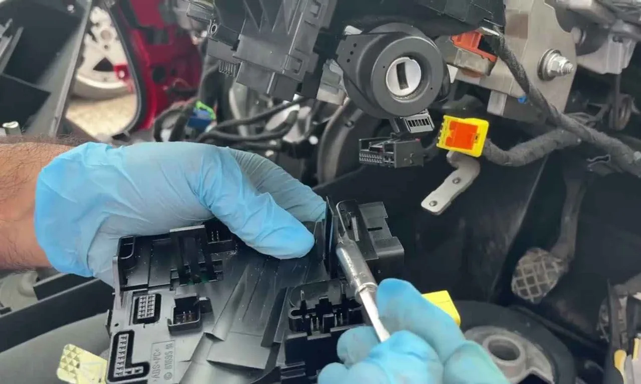 Technician working around an exposed ignition lock and steering column