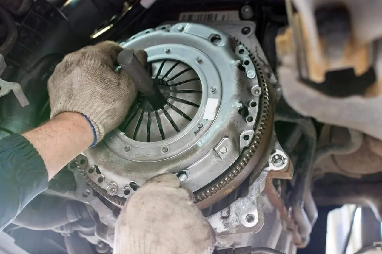 Technician fitting a clutch pressure plate with the transmission removed
